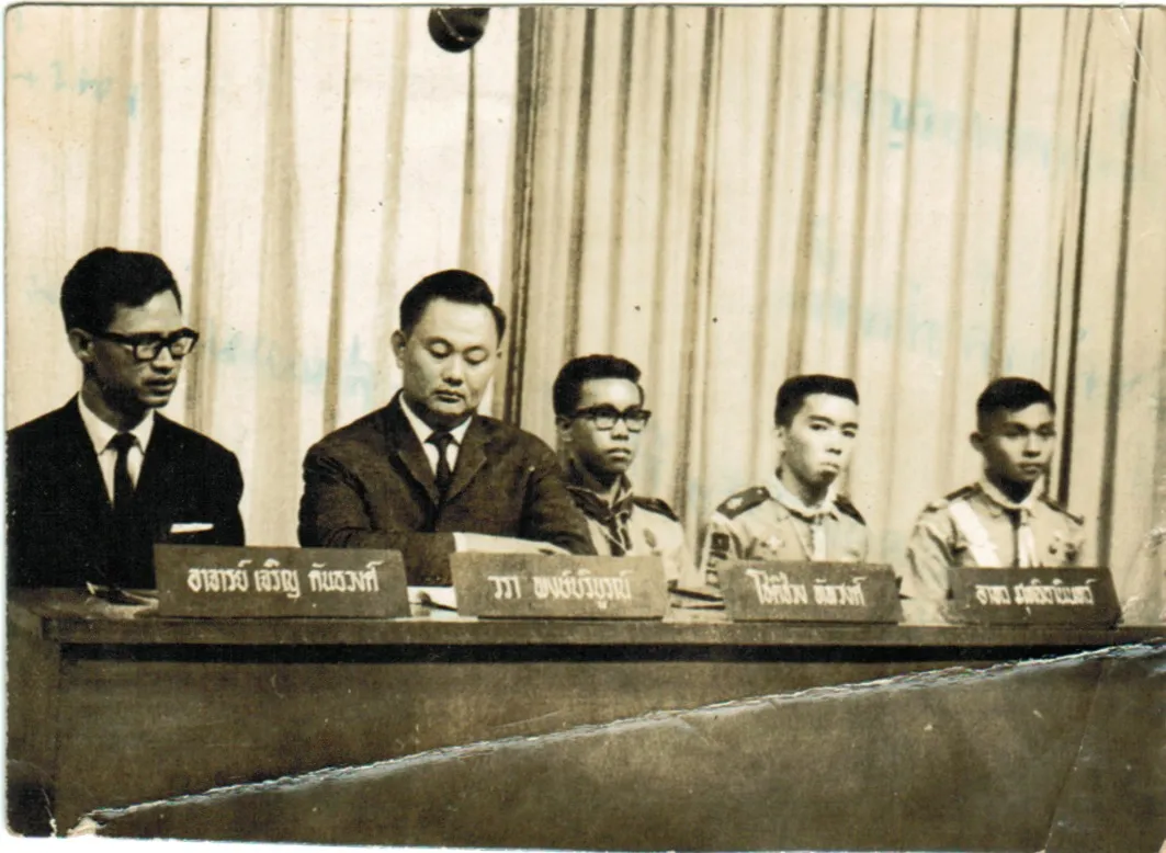 ลุงขาวนั่งร่วมรายการโทรทัศน์ที่โต๊ะเสวนาพร้อมป้ายชื่อ วรา พงษ์บริบูรณ์ เคียงข้างวิทยากรและเยาวชนในเครื่องแบบ