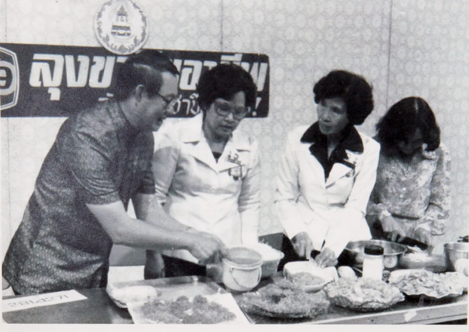 ลุงขาวสาธิตการทำอาหารร่วมกับผู้ร่วมรายการหน้าฉากที่มีป้าย ลุงขาวไขอาชีพ ในสตูดิโอโทรทัศน์