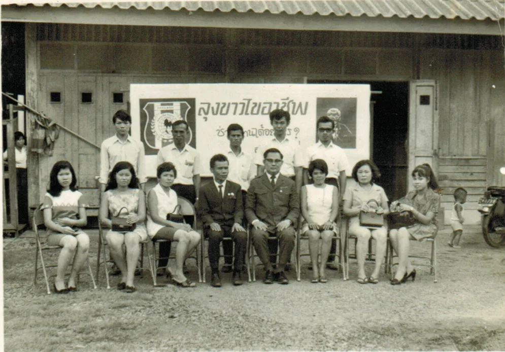 ภาพหมู่สมาชิกและวิทยากรของ “ลุงขาวไขอาชีพ” ถ่ายร่วมกันหน้าป้ายชื่อองค์กรในยุคบุกเบิก